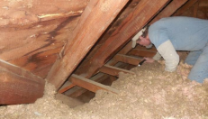 Worker in attic inspecting insulation