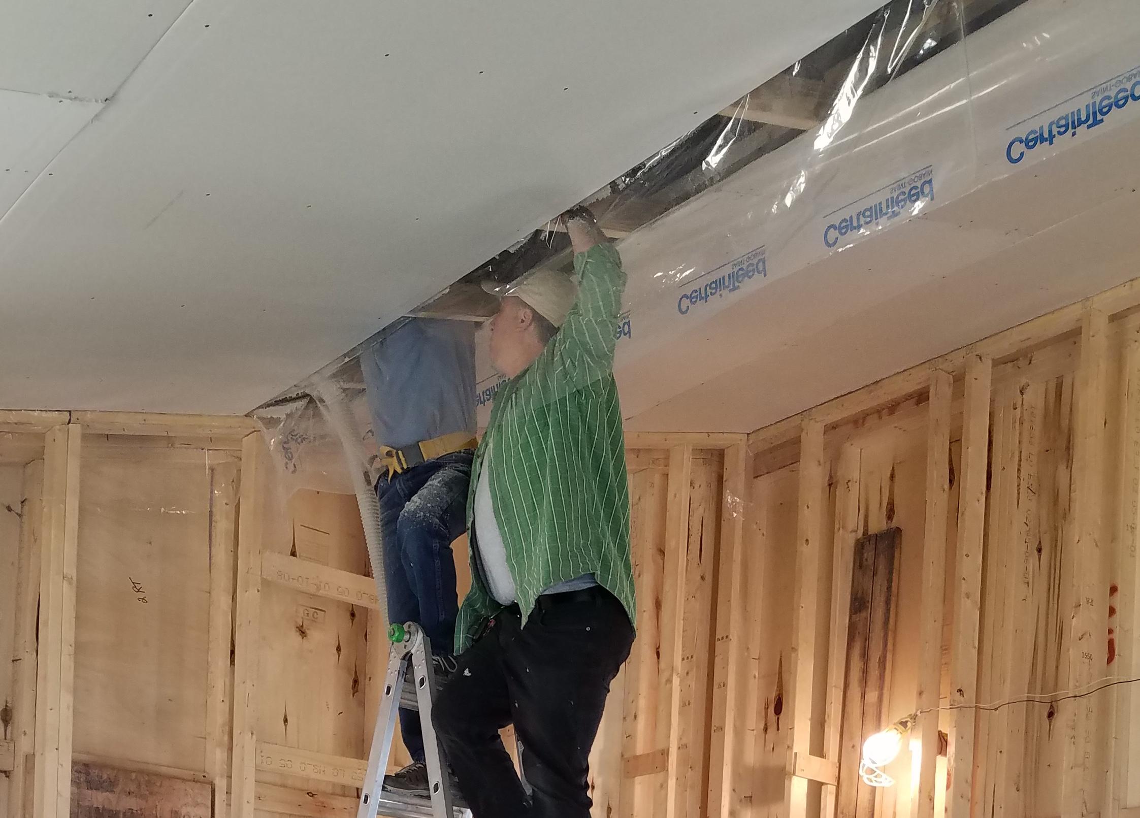 Accurate-Airtight Exteriors' President, Torrance Kramer, working from a ladder to install cellulose insulation