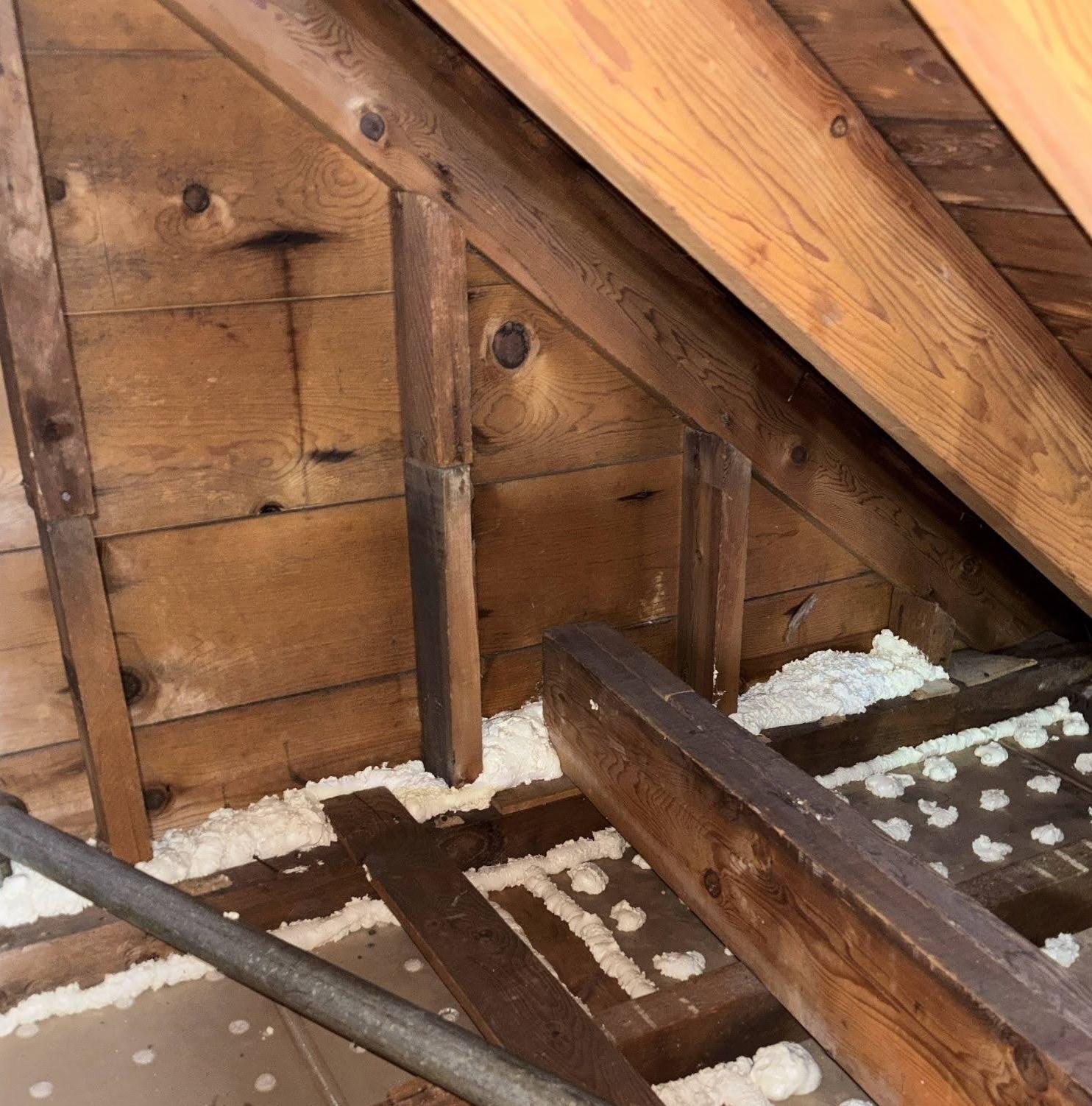 Spray foam insulation being used to air seal parts of attic after insulation removal